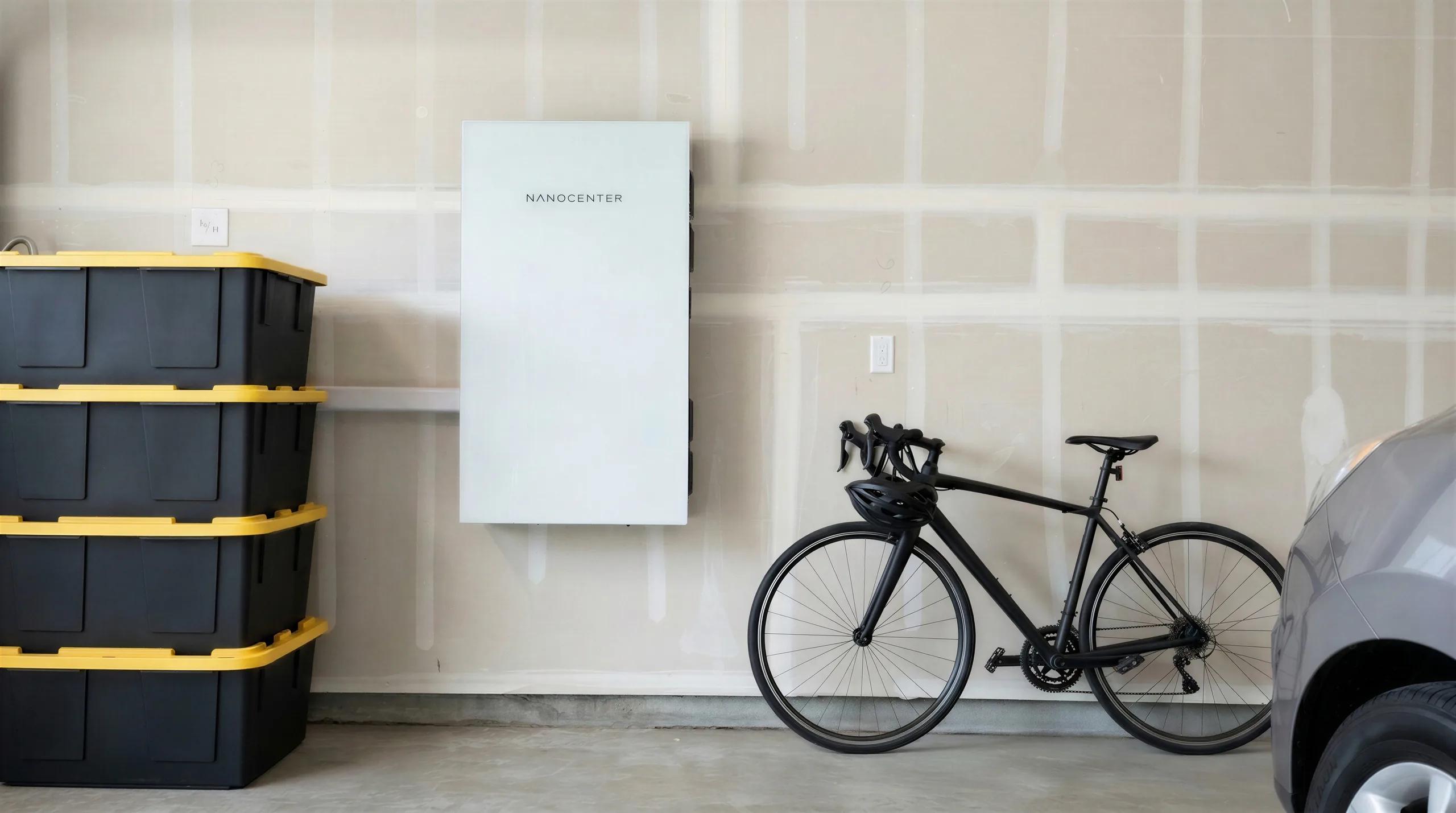 A Nanocenter unit mounted on a garage wall between stacked storage bins and a bicycle, with a parked car alongside.